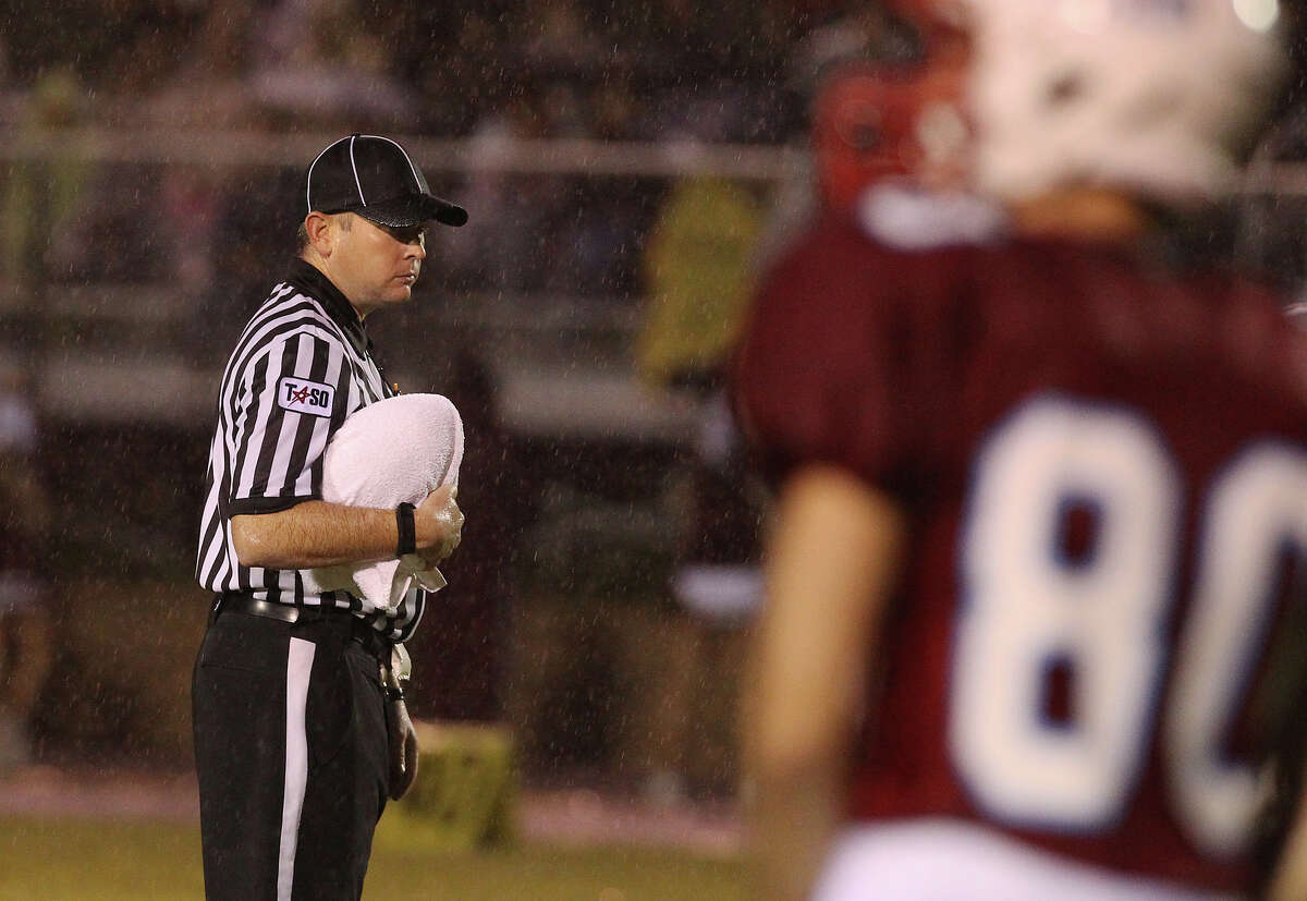 A game official protects the game ball with a towel from the rain before the start of the Antonian-Devine football game at Antonian High School on Friday, Sept. 28, 2012.