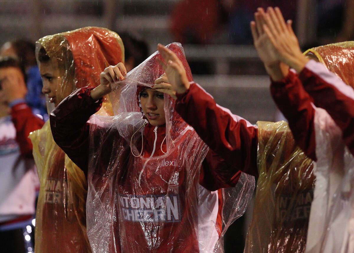 Antonian cheerleaders wear rain ponchos to guard against the rain during the Antonian-Devine football game at Antonian High School on Friday, Sept. 28, 2012.