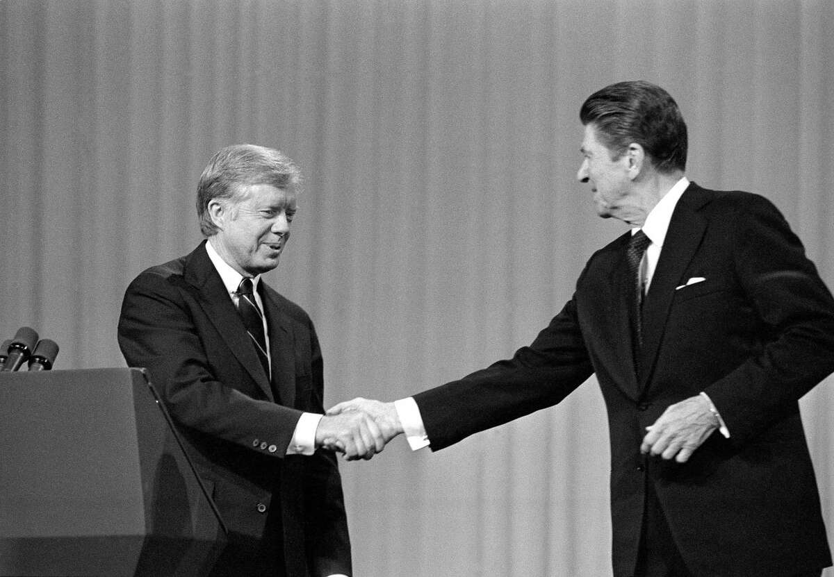This Oct. 28, 1980 black-and-white file photo shows President Jimmy Carter, left, and Republican Presidential candidate Ronald Reagan shake hands after debating in the Cleveland Music Hall in Cleveland. In presidential politics, everybody's searching for "the moment." The campaigns don't know when or how it will come, but they watch for something _ awkward words or an embarrassing image _ that can break through and become the defining symbol of the other guy's flaws. Now all eyes are on the series of three presidential debates that starts Wednesday. (AP Photo/Madeline Drexler, File)