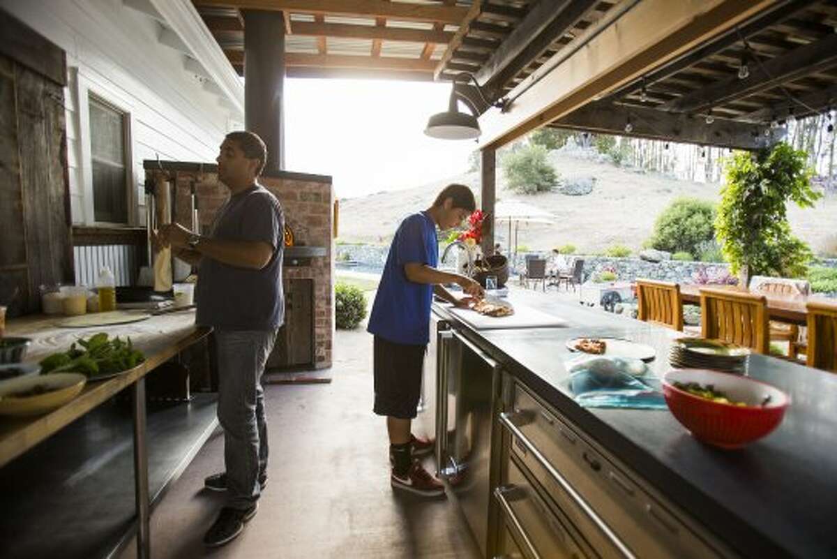 Chef Michael Mina, left, and son Sam make a pizza in their home's outdoor kitchen. (Stephen Lam / Special to The Chronicle)