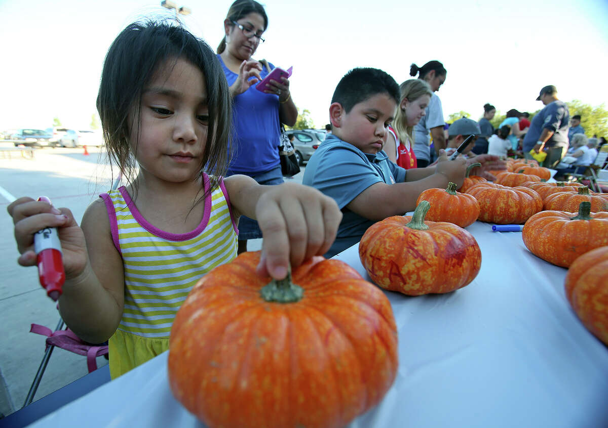 Mia Cavazos joins her older brother Tia Cavazos in pumpkin painting as the Athlos Leadership Academy and the Pecan Valley Neighborhood Association host a National Night Event at the campus on October 7, 2014.