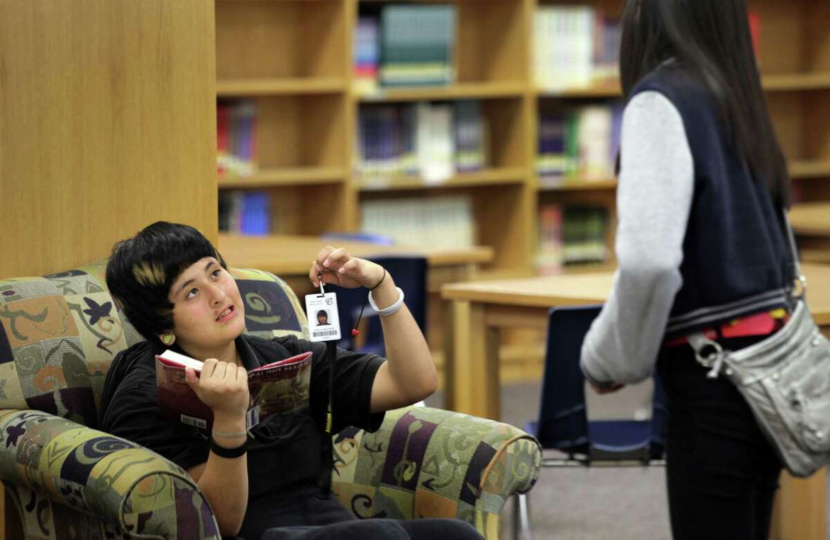 Kayla Saucedo, left, shows her ID badge to a fellow student. Students at Anson Jones Middle School are using new identification badges that have a built in chip that enables school attendance workers to see where a student is while on campus. Oct. 1, 2012.