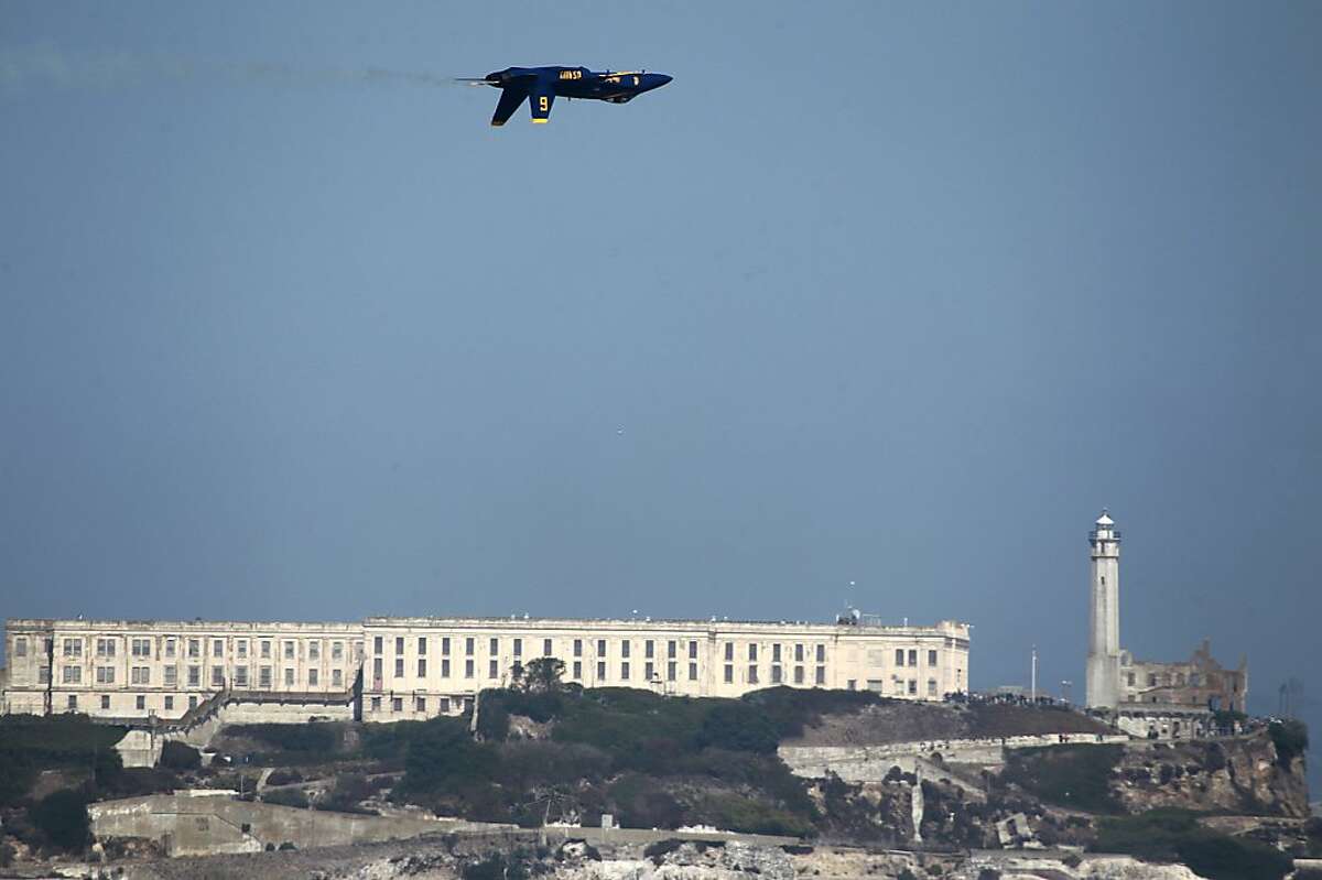 A Blue Angels F/A 18 jet flies inverted past Alcatraz during a practice session for Saturday's performance in San Francisco, Calif. on Thursday, Oct. 4, 2012.