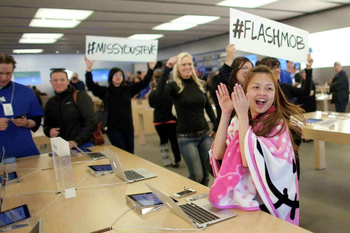 A customer applauds as people dance to Gangnam Style during a flash mob honoring Apple co-founder Steve Jobs on Friday at the University Village Apple Store in Seattle. October 5 is the one-year anniversary of the death of the innovative technology leader. The flash mob was organized by Filter digital agency and participants wore Jobs' signature black turtlenecks, jeans and glasses. The event payed homage to Jobs' quote during a 2005 speech at Stanford University: "Stay hungry, Stay foolish!"