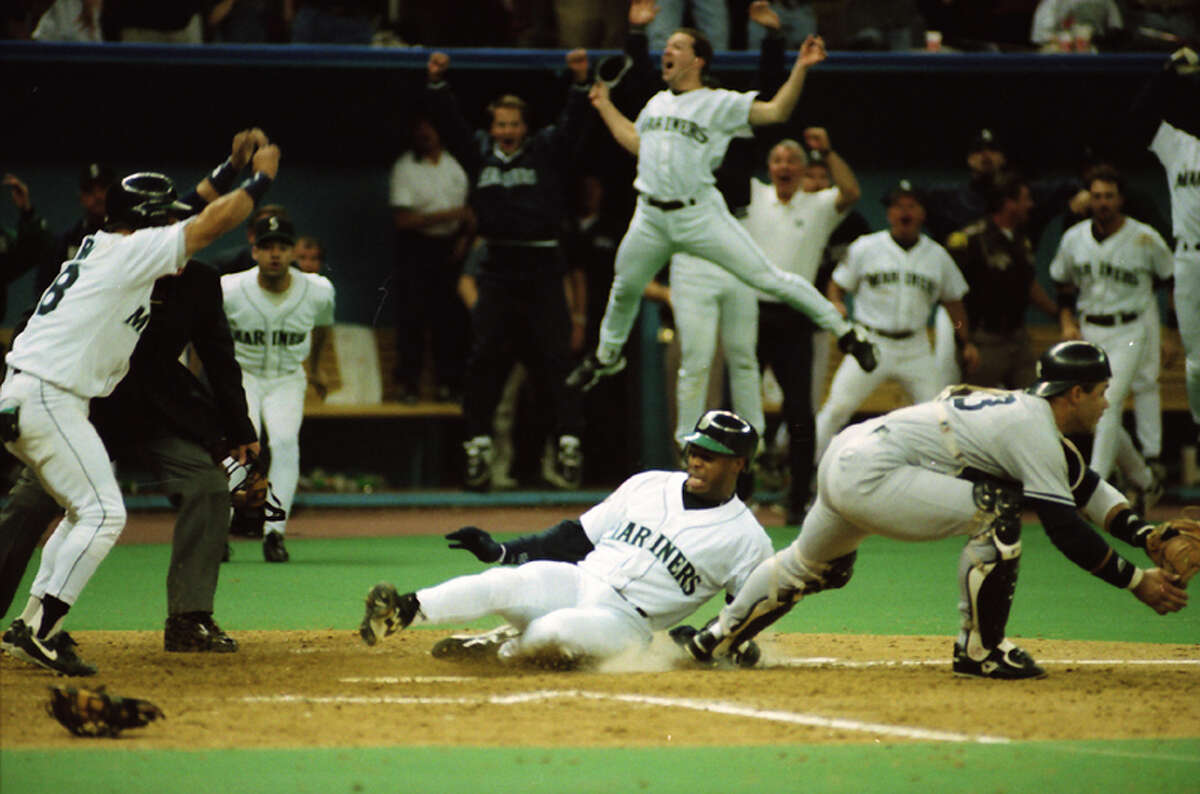 Ken Griffey Jr. slides into home as teammates begin to celebrate the Mariners' win over the New York Yankees in Game 5 of the 1995 AL Division Series on Oct. 8, 1995.