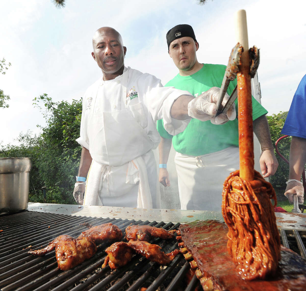 At left, chef Francis Collymore of Big Bubba's BBQ, spreads Memphis barbecue sauce on pork ribs while Raymond Lopez, an assistant chef, looks on, during the second annual Greenwich Food and Wine Festival at Roger Sherman Baldwin Park in Greenwich, Saturday, Oct. 6, 2012. The restaurant is located at the Mohegan Sun Resort and is owned by Greenwich resident Godfrey Polistina. The event benefits the Hole in the Wall Gang Camp, a nonprofit that runs camps for children coping with cancer, sickle cell anemia and other serious illnesses.