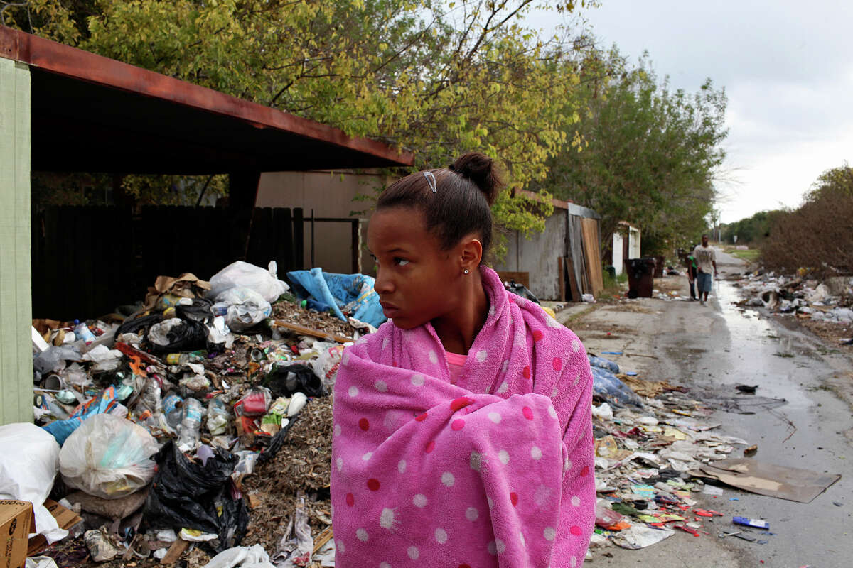 Nila Garrett, 13, watches as friends look for the source of running water behind a home they said was empty as they walked through an alley lined with trash and discarded furniture in the Camelot II neighborhood in Northeast San Antonio on Friday, Nov. 23, 2012. They found an outside faucet running and turned it off.