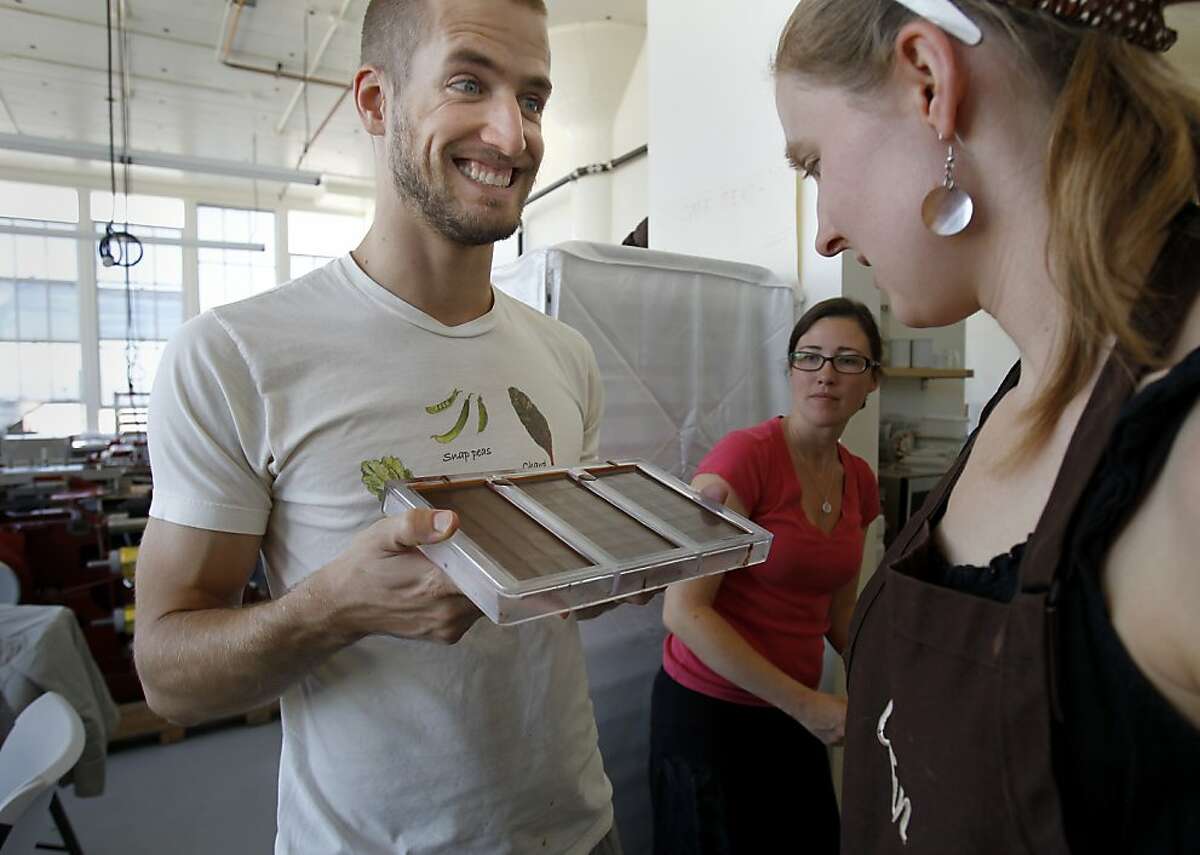 Dandelion chocolatier Tod Chubrich (left) shows some finished bars to Caitlin Lacey (right).