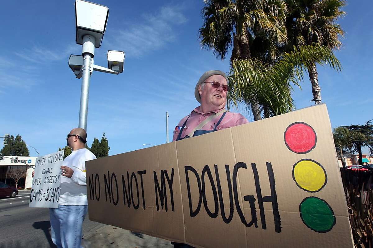 Roger Jones right and Howard Mora left stand under a red light camera as they took part in a protest agianst the cameras Saturday, February 4, 2012 in Fremont California.