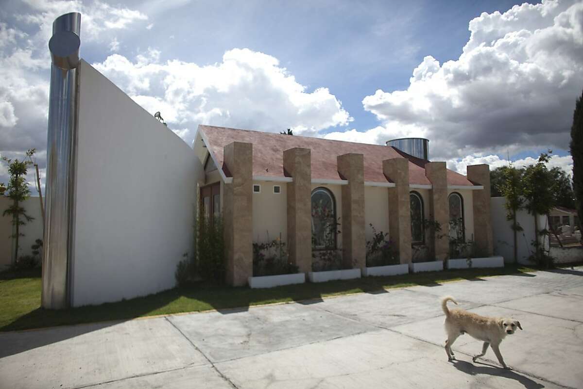A dog walks near a tomb that was allegedly built by Heriberto Lazcano Lazcano, alleged leader of the Zetas, at a cemetery in the neighborhood of Tezontle in Pachuca, Mexico, Tuesday, Oct. 9, 2012. The tomb is a copy of an actual church in Tezontle, which at one point had a plaque naming Lazcano as the donor. Mexico's Navy says fingerprints confirm that cartel leader Lazcano, an army special forces deserter, was killed Sunday, Oct. 7, 2012 in a firefight with marines in the northern state of Coahuila on the border with the Texas. (AP Photo/Alexandre Meneghini)
