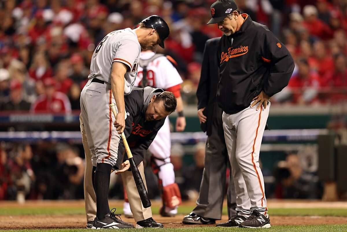Hunter Pence of the San Francisco Giants is checked out by a team trainer and manager Bruce Bochy in the 10th inning against the Cincinnati Reds in Game Three of the National League Division Series at the Great American Ball Park on October 9, 2012 in Cincinnati, Ohio. (Photo by Andy Lyons/Getty Images)