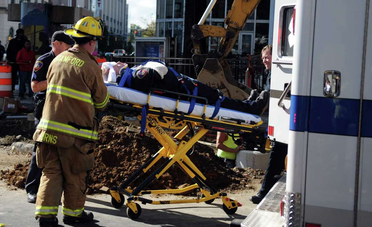 A Stamford police officer is wheeled on a stretcher into a waiting ambulance after he was hit by a car while engaged in a foot pursuit on Wednesday, October 10, 2012. The accident occured on Bedford Street near the Ferguson Library.