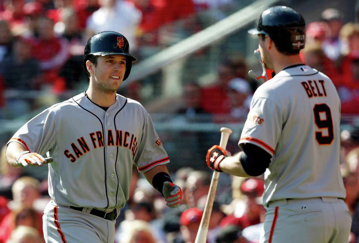 San Francisco Giants' Buster Posey is congratulated by Brandon Belt (9) after Posey hit a grand slam against the Cincinnati Reds in the fifth inning of Game 5 of the National League division baseball series, Thursday, Oct. 11, 2012, in Cincinnati. (AP Photo/David Kohl)