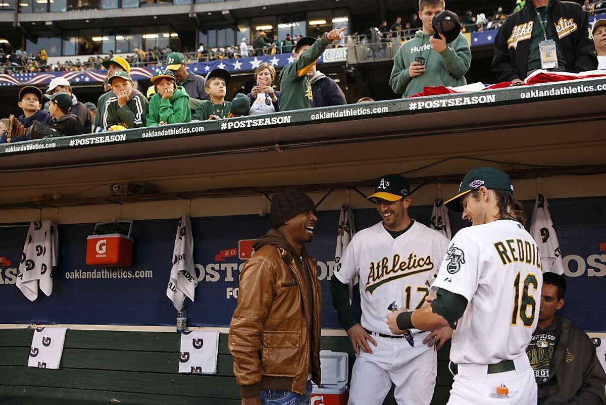 Josh Reddick, right, and Adam Rosales, center, laugh with MC Hammer, left, in the dugout before Hammer threw out the first pitch for the A's game against the Tigers. The Oakland Athletics played the Detroit Tigers in game 5 of the ALDS at O.co Coliseum in Oakland, Calif. on Thursday, October 11, 2012.
