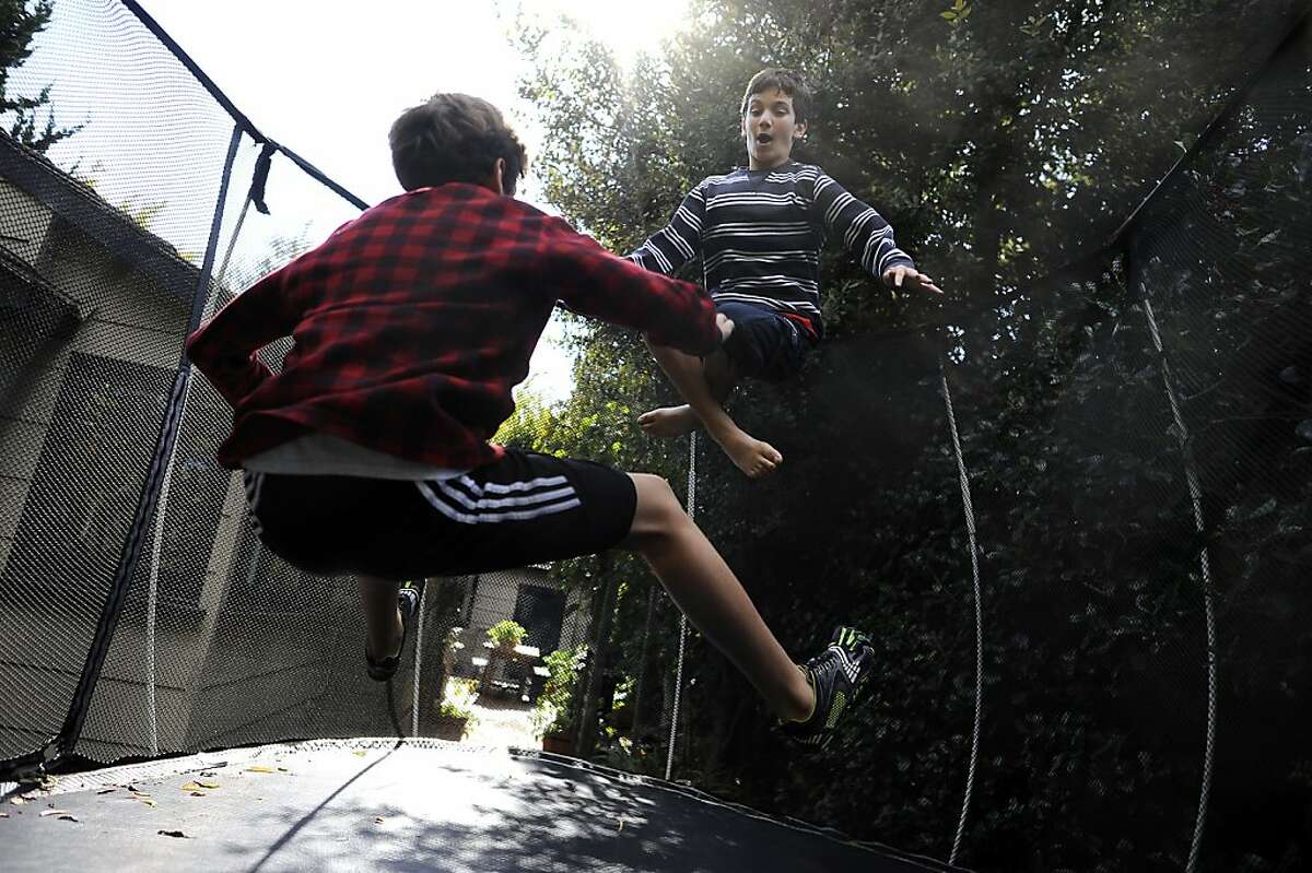 Colman Chadmon (right) jumps on the trampoline with his brother Aidan in their back yard at their home in Palo Alto on Tuesday, October 10th, 2012. Colman has been asked to leave his middle school in Palo Alto, Calif. because he has the genetic markers for cystic fibrosis and the school doesn't want him near another student who is already there with CF.