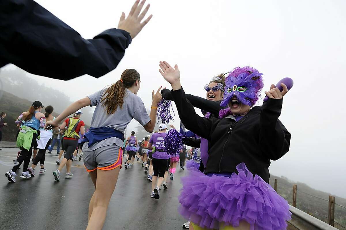 Amanda Pineiro(R) and Janet Perkins of Team in Training, part of the Leukemia and Lymphoma Society, give high-fives to runners as they pass during the 2012 Nike Women?•s Marathon & Half Marathon in San Francisco, CA on Sunday, October 14th, 2012