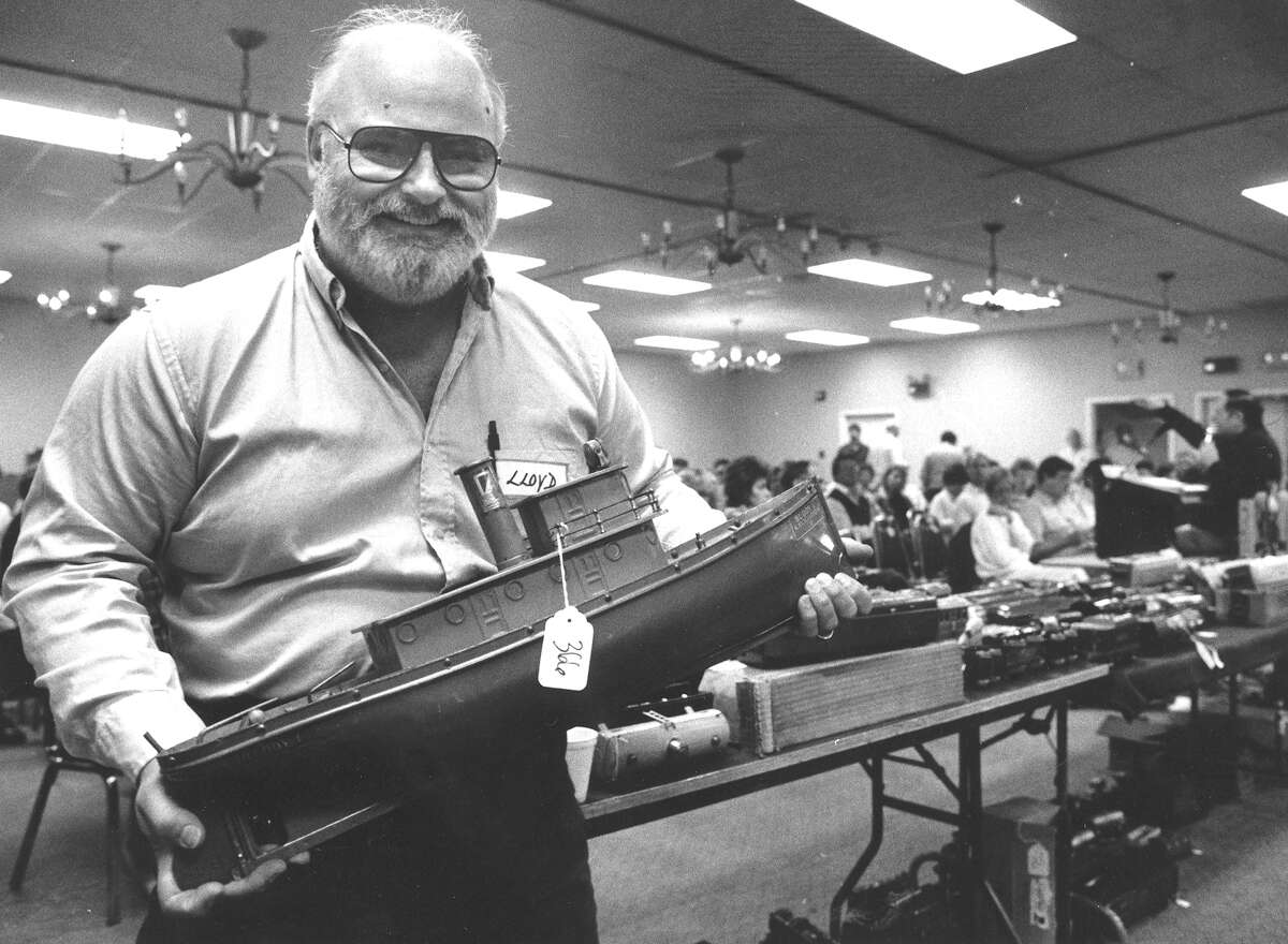 Stamford native Lloyd Ralston shows off an antique tugboat that sold for $10,000 early in the Oct. 17, 1987, toy auction he organized. The two-day auction, which drew buyers from as far away as Germany, continues in the background. It was expected to gross $250,000, with one-quarter of reciepts, or about $62,500 for Ralston.