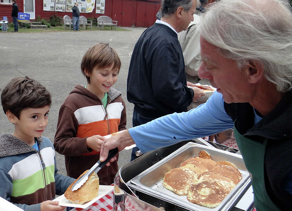 Peter Wormser, a Wakeman Town Farm volunteer, serves pancakes to William and Henry Matar, ages 9 and 7, of Westport, at the farm's annual pancake breakfast Sunday.