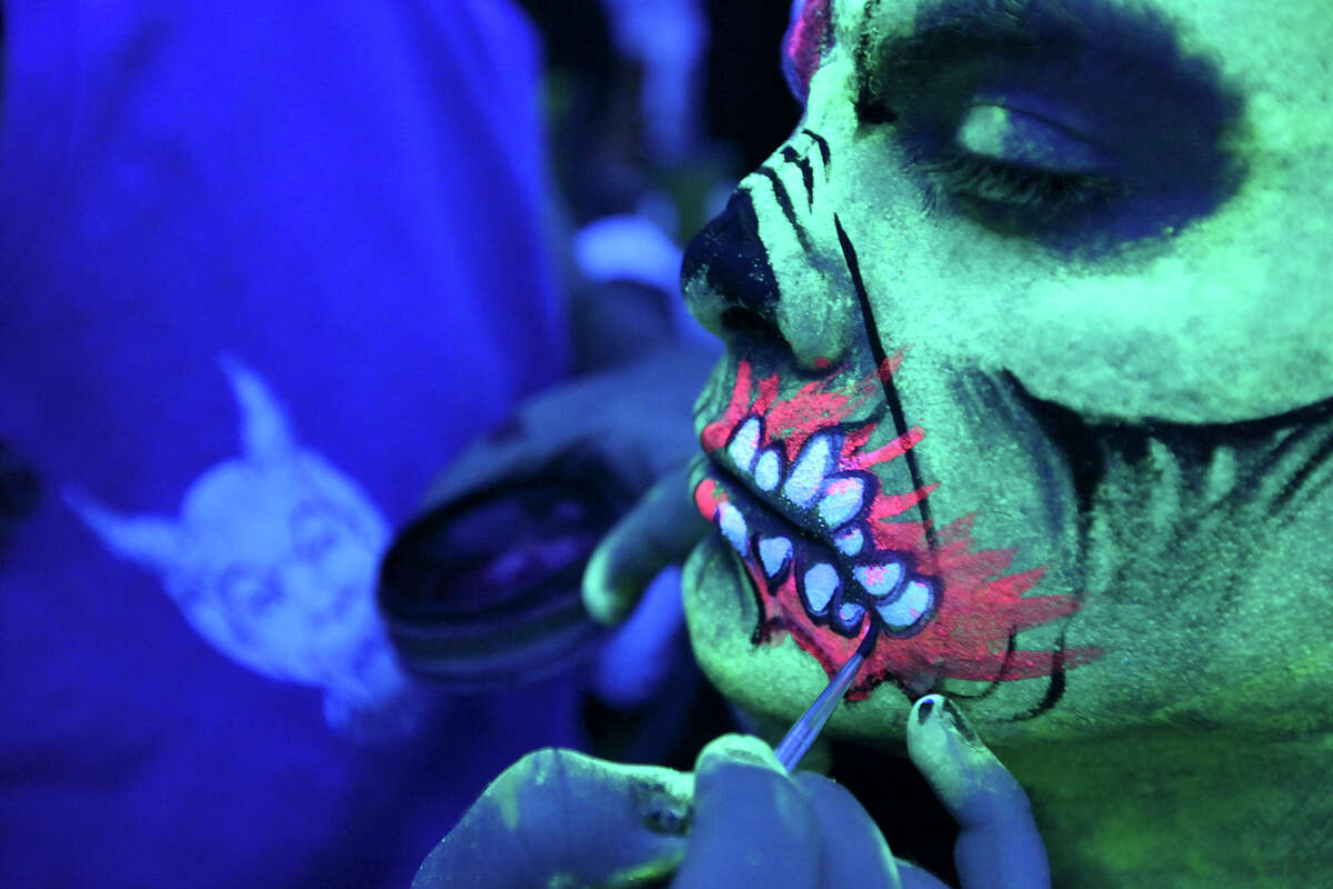 Makeup artist Burns applies zombie makeup to under black-light.