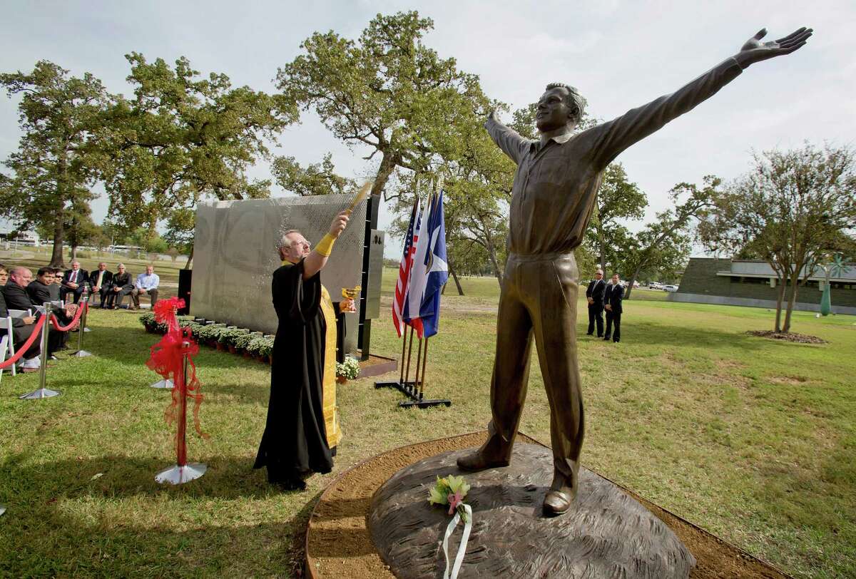 Father Lubomir Kupecz blesses the statues of Yuri Gagarin and memorial to John Glenn with holy water at the city of Houston's parks department headquarters, which was the original NASA headquarters in Houston, Texas.