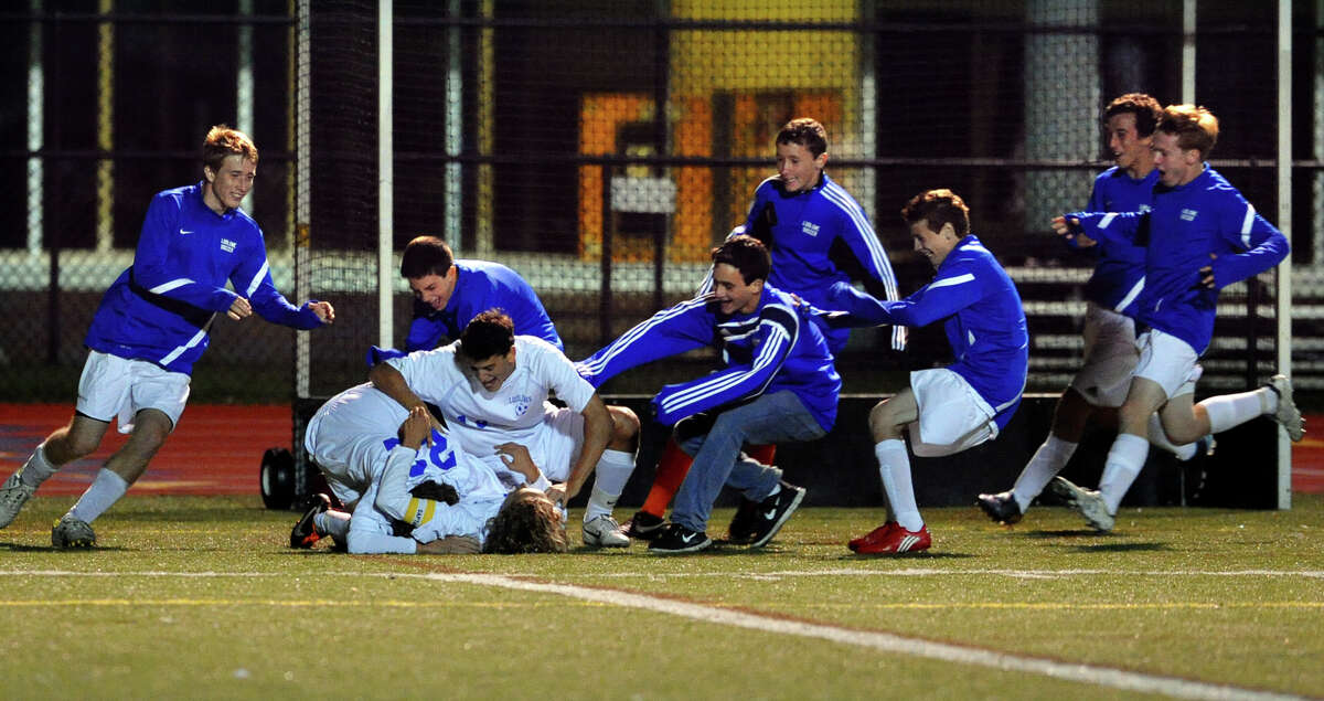 Teammates of Fairfield Ludlowe's #10 Tobias Gimand rush in to celebrate his goal winning shot, during boys soccer action against Staples in Fairfield, Conn. on Tuesday October 16, 2012.