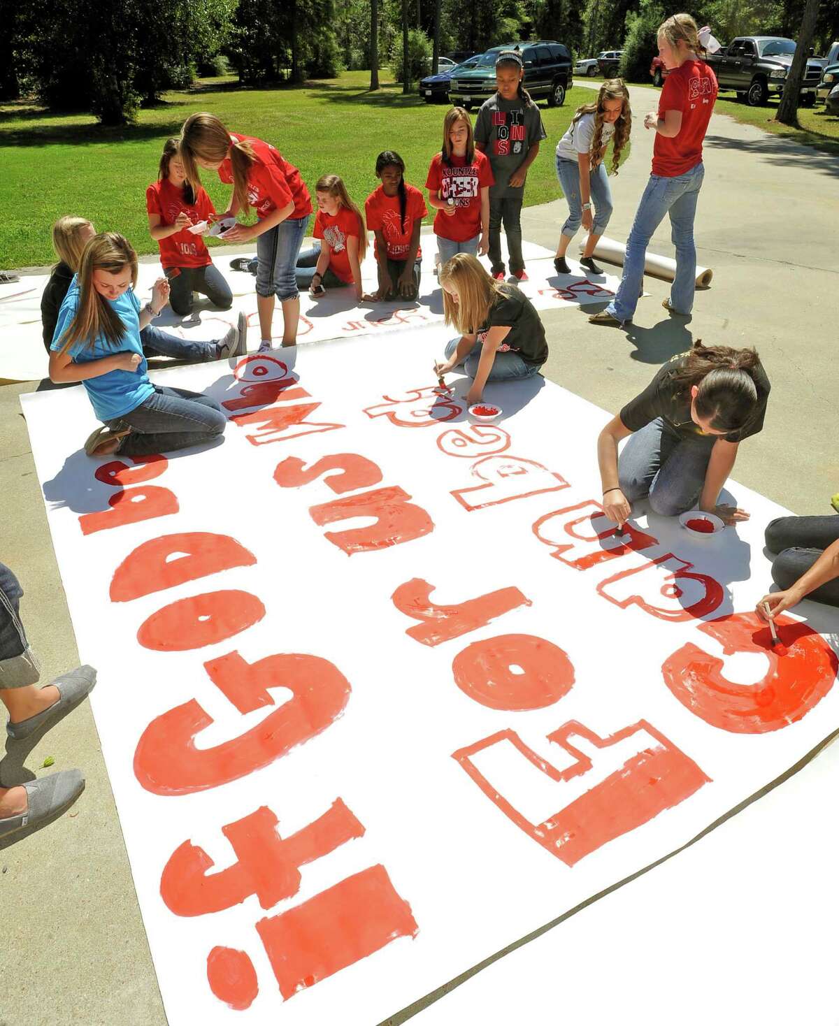 File - In this Sept. 19, 2012 file photo, Kountze High School cheerleaders and other children work on a large sign in Kountze, Texas. Texas Attorney General Greg Abbott announced Wednesday that he is intervening in a lawsuit that cheerleaders filed against the school district. The district told the cheerleaders to stop using Bible verses at football games after the Freedom From Religion Foundation complained. (AP Photo/The Beaumont Enterprise, Dave Ryan, File)
