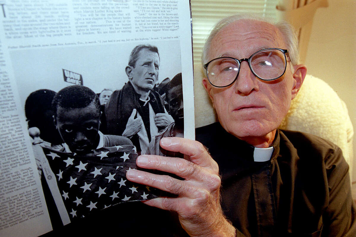 Father Sherrill Smith holds a Saturday Evening Post from 1965 with a photo of him in the Selma-to Montgomery march.