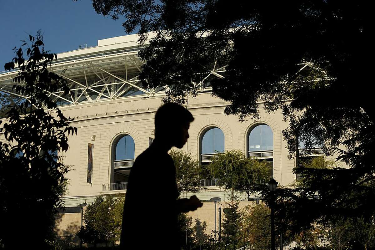 With Cal's Memorial Stadium in the background, a student waits for a bus on Piedmont Ave. on Thursday, Oct. 18, 2012, in Berkeley, Calif.