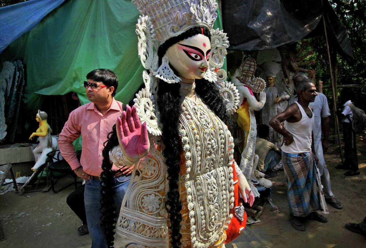 A Hindu devotee, left, waits for a transport to carry an idol of Goddess Durga for the occasion of Durga Puja festival, in New Delhi, India, Friday, Oct. 19, 2012. The five-day Durga Puja festival begins on Oct. 20 and ends with the immersion of idols in water bodies on Oct. 24. (AP Photo/Manish Swarup)