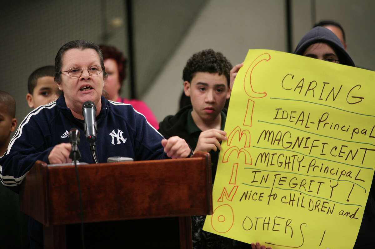 Robin Mastro of Bridgeport addresses the Board of Education in support of Thomas Hooker School principal Andrew Cimmino, on paid leave since September, as Hooker students Edgar Feliciano, 12, and Monet Monterroso hold up a sign, at the Bridgeport Board of Education meeting at the Aquaculture School on Monday, March 22, 2010. Cimmino is now challenging is firing in court.