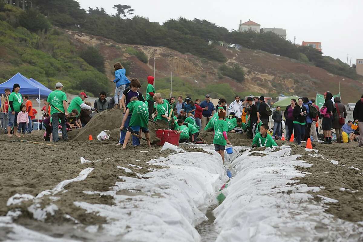 A plastic tarp reservoir filled with water leads to Miraloma Elementary School team members who are working on their sand castle.