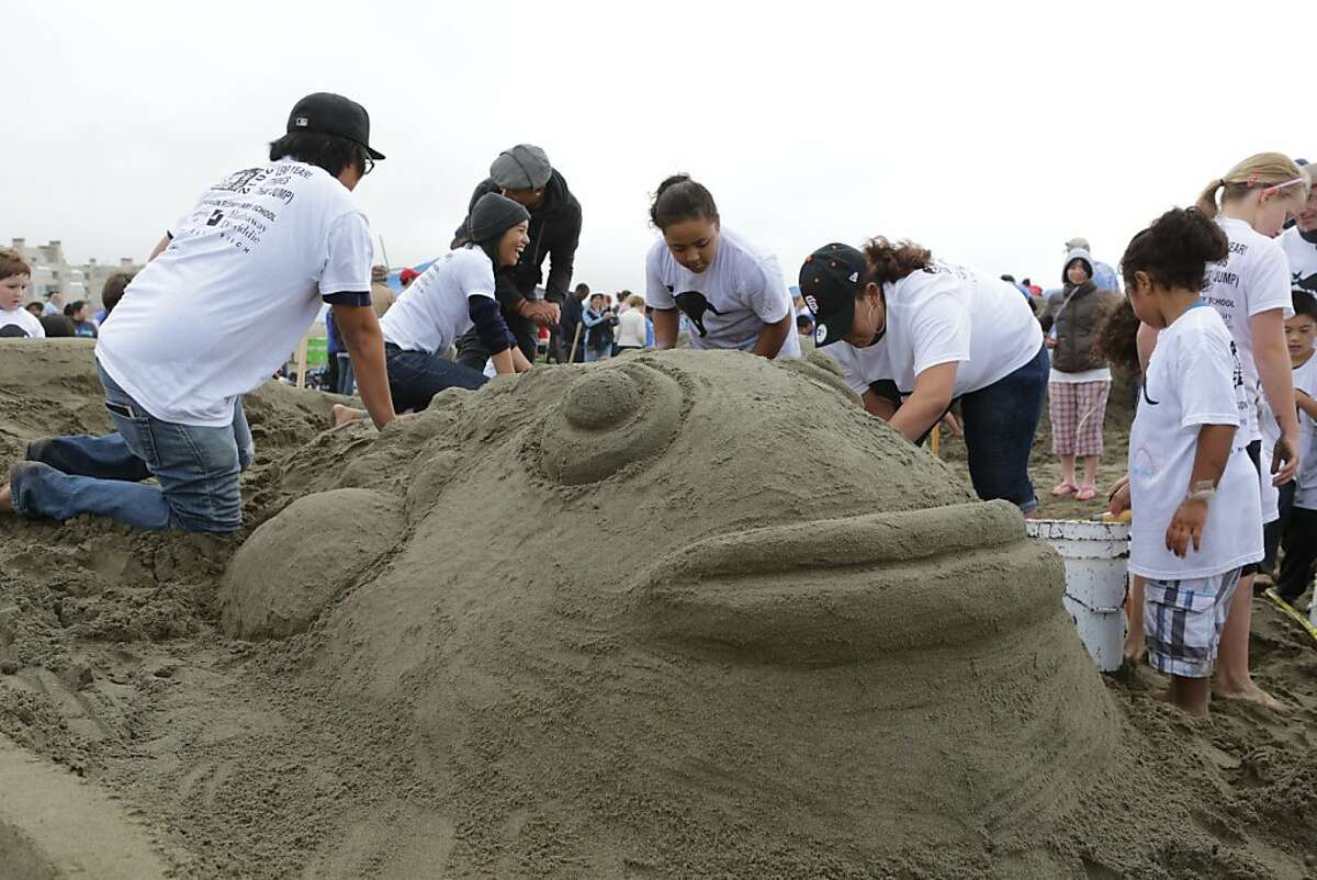 Team members from Jefferson Elementary School help to carve one of two fish jumping out of 3D glasses. Hundreds of people turned out for the annual LEAP Sand Castle Contest at Ocean Beach in San Francisco on Saturday. The charity event supports arts in education programs.