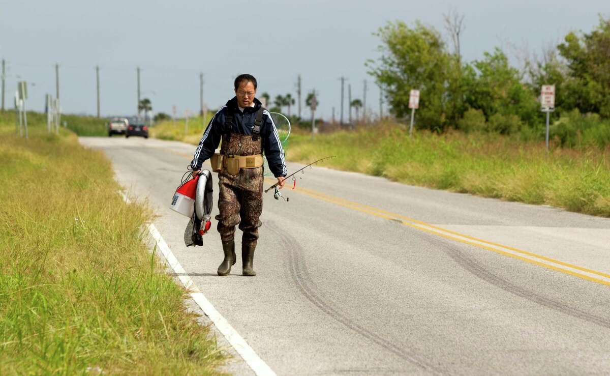 Joe Zeng, of Missouri City, walks along Seawolf Parkway after fishing on Pelican Island Thursday, Oct. 18, 2012, in Galveston. A new bridge to the island would enable rerouting the highway to divert traffic north of Texas A&M Galveston.