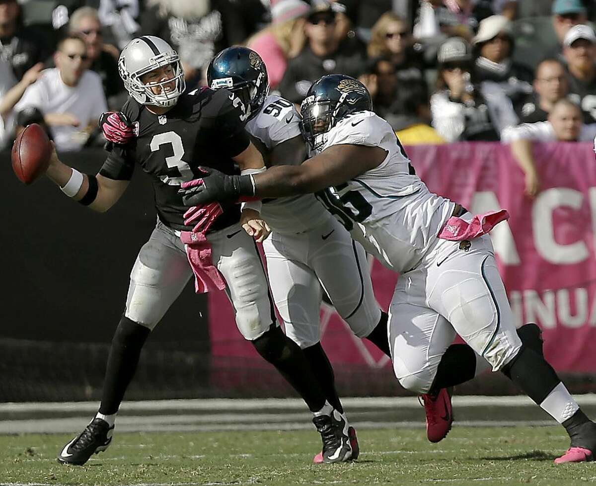 Oakland Raiders quarterback Carson Palmer (3) looks to pass as Jacksonville Jaguars defensive end Andre Branch (90) and defensive tackle Terrance Knighton (96) try to sack him during the second half of an NFL football game, Sunday, Oct. 21, 2012, in Oakland, Calif. (AP Photo/Marcio Jose Sanchez)