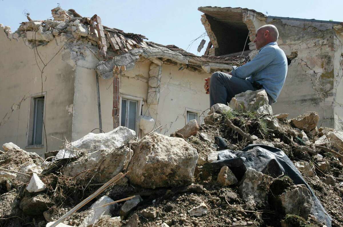 FILE - In this April 7, 2009 file photo a man sits on rubbles in the village of Onna, a day after a powerful earthquake struck the Abruzzo region in central Italy. An Italian court Monday, Oct. 22, 2012 has convicted seven scientists and experts of manslaughter for failing to adequately warn citizens before an earthquake struck central Italy in 2009, killing more than 300 people. The court in L'Aquila Monday evening handed down the convictions and six-year-prison sentences to the defendants, members of a national "Great Risks Commission." In Italy, convictions aren't definitive until after at least one level of appeals, so it is unlikely any of the defendants would face jail immediately. Scientists worldwide had decried the trial as ridiculous, contending that science has no way to predict quakes. (AP Photo/Alessandra Tarantino, File)