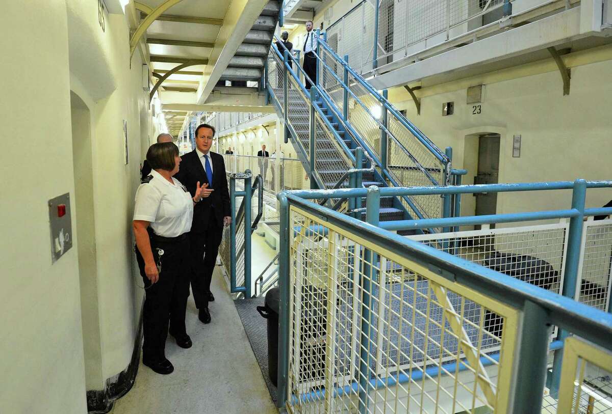 Britain's Prime Minister David Cameron, right, is escorted around C wing by prison officer Margaret Vaughan during his visit to Wormwood Scrubs Prison in west London Monday Oct. 22, 2012. (AP Photo/Paul Hackett, Pool)