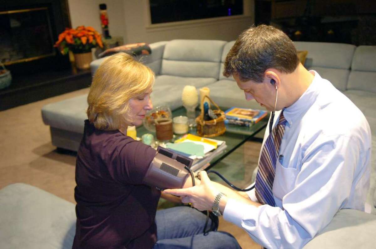 Dr. Thomas Pellechi checks Carolyn Altieri's blood pressure during a visit to her Greenwich home Tuesday evening, Dec. 8, 2009. Pellechi is a Greenwich based doctor and one of few in town who makes house calls.