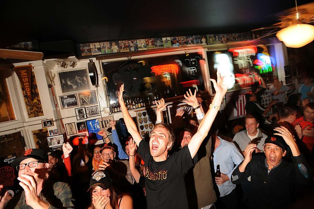Watching the first game of the World Series at Double Play, Giants fan Tyler Costin cheers as Pablo Sandoval scores on Wednesday, Oct. 24, 2012, in San Francisco.