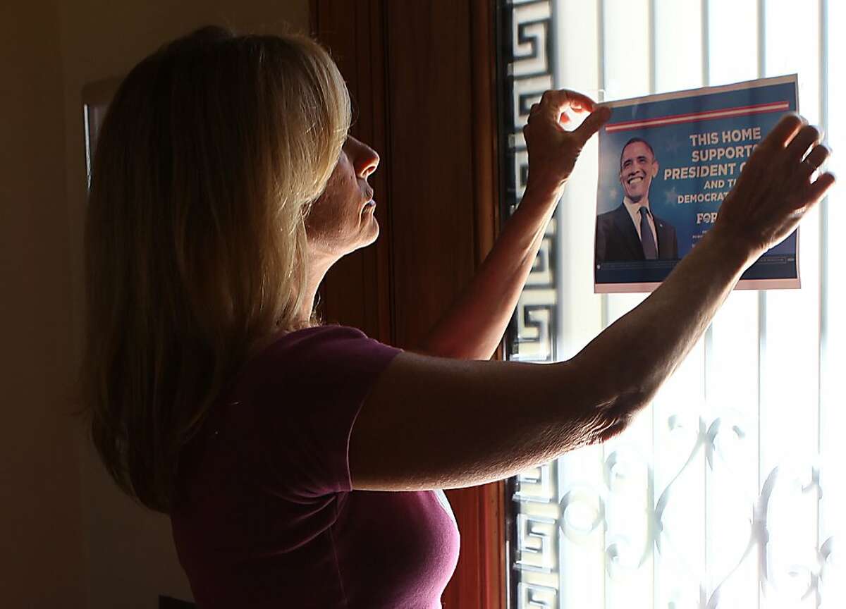 Obama campaign volunteer Kay Edelman switching placement of an Obama poster on her front door in San Francisco, Calif., as she mentions how close the presidential polls are on Thursday, October 25, 2012.