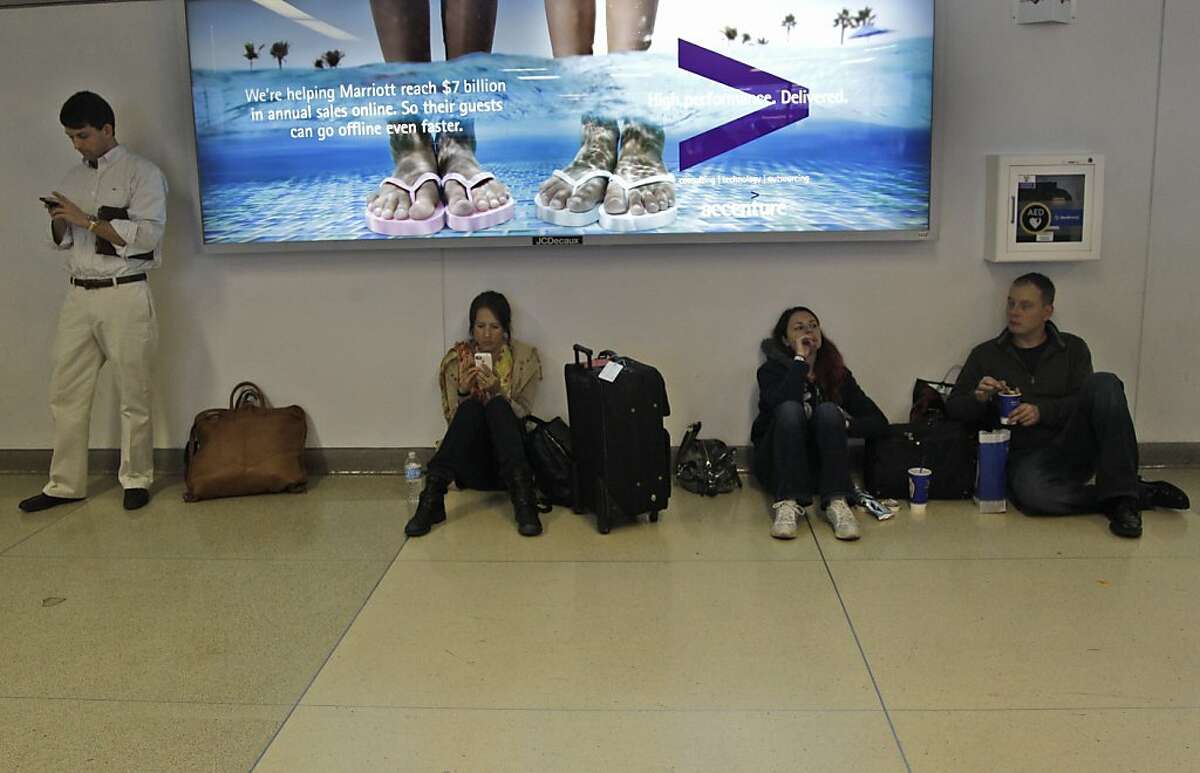 Passengers wait for their flight at at LaGuardia airport, Sunday, Oct. 28, 2012 in New York. Tens of thousands of residents were ordered to evacuate coastal areas Sunday as big cities and small towns across the Northeast buttoned up against the onslaught of a superstorm. (AP Photo/Mary Altaffer)
