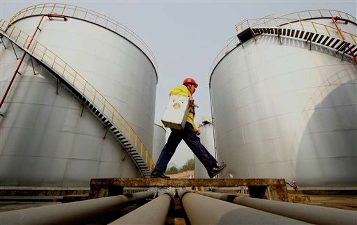 FILE - In this Thursday, Jan. 28, 2010 file photo, a worker walks past tanks at a Petrochina storage base in Suining, in southwest China's Sichuan province. A big shift is happening in Big Oil: an American giant now ranks second to a Chinese upstart. Exxon Mobil is pumping less oil than PetroChina, a company formed just 13 years ago by the Chinese government to better compete for the world's oil and natural gas. On March 29, 2012, the shift is expected to become official when the Beijing company announces that it produced more crude last year than its 130-year-old Texas rival.
