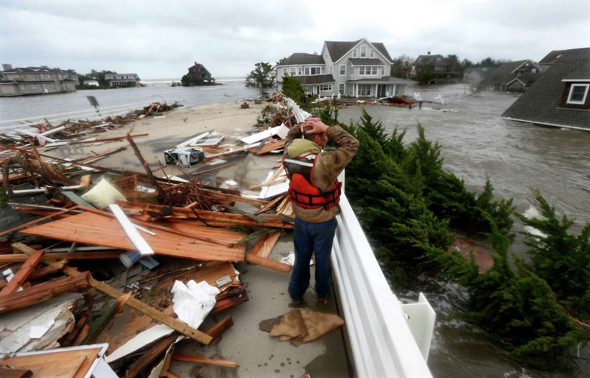 Brian Hajeski, 41, of Brick, N.J., reacts as he looks at debris of a home that washed up on to the Mantoloking Bridge the morning after superstorm Sandy rolled through, Tuesday, Oct. 30, 2012, in Mantoloking, N.J. Sandy, the storm that made landfall Monday, caused multiple fatalities, halted mass transit and cut power to more than 6 million homes and businesses. (AP Photo/Julio Cortez)
