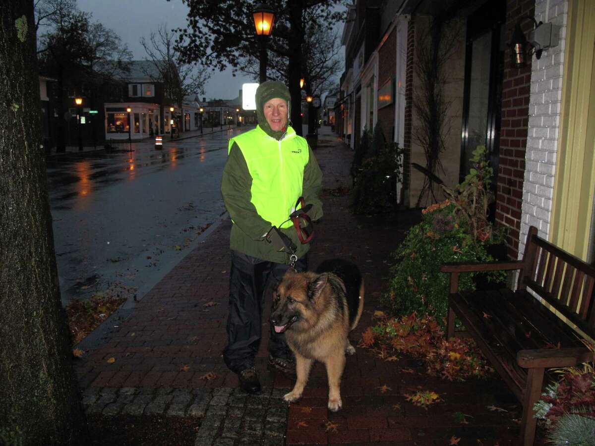 New Canaan resident Sherman Bull and Denali take a walk on Elm Street as Hurricane Sandy revved up Monday night.