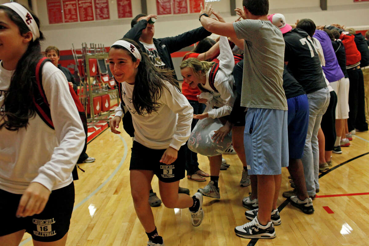 The Churchill Volleyball team runs through a tunnel made by students to celebrate their win against New Braunfels Canyon in a Class 5A first round playoff match at Judson High School on Tuesday, Oct. 30, 2012.
