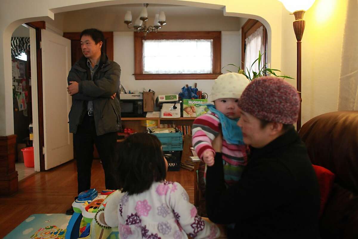 Mark Gin (left) talks with his wife, Jenny Gin (right) in their living room with their daughters Emily Gin, 8 months, (second from right) and Angela Gin, 3, (second from left) in San Francisco on Tuesday, October 30, 2012.
