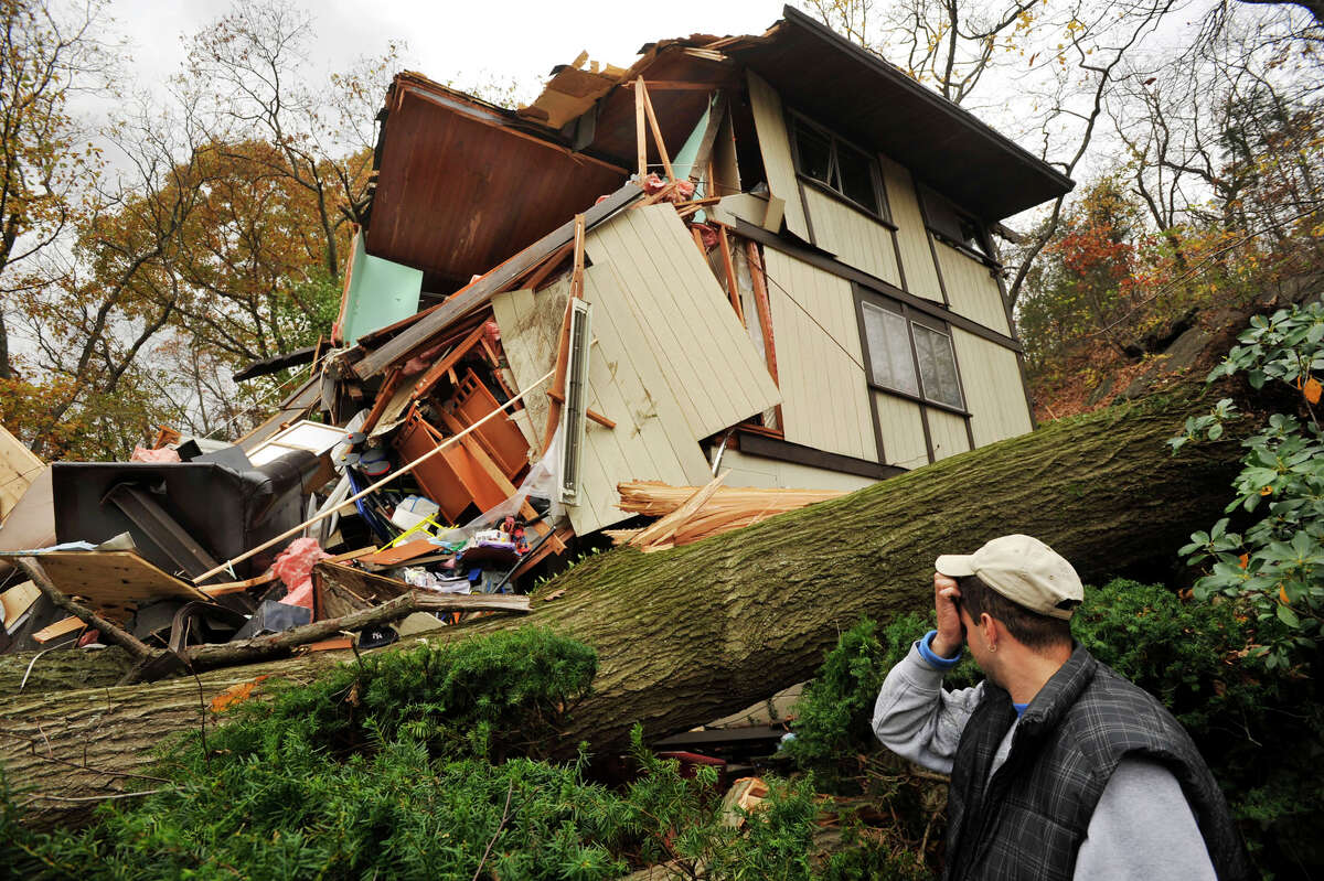 Reynaldo Lopez surveys the damage to his family's home in Danbury on Wednesday, Oct. 31, 2012. The house sustained the damage due to a large tree falling on it Monday evening because of storm Sandy. The family was inside their home when it was hit, but nobody was hurt.