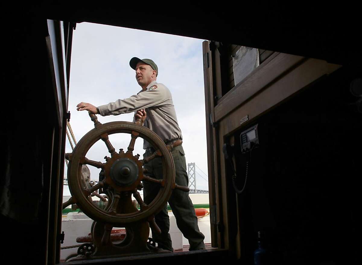 Jason Rucker, captain of the Alma, steers the historic scow schooner past the Bay Bridge on a voyage from the Hyde Street Pier to India Basin, in San Francisco, Calif. on Thursday, Nov. 1, 2012. Built in the year 1891, the Alma once plied the shallow waters of the Sacramento-San Joaquin delta hauling heavy cargo.