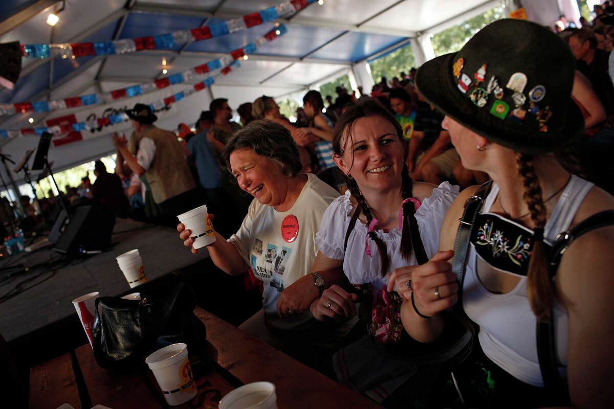Kathy Rubey, of New Ulm, MN, from left, Jamie Logsdon and Whitney Welsch, both of Austin, join arms to sway back and forth together as the Alex Meixner Band plays during Wurstfest in New Braunfels on Saturday, Nov. 3, 2012.