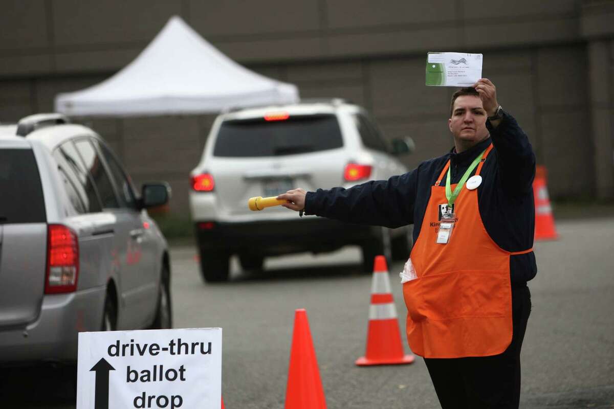 Jeffrey McGinn guides cars to a ballot drop box at the King County Elections ballot processing facility in Renton on Election Day, Tuesday, November 6, 2012. Voters can main in ballots or drop them off.  The King County Council has just voted for prepaid postage.