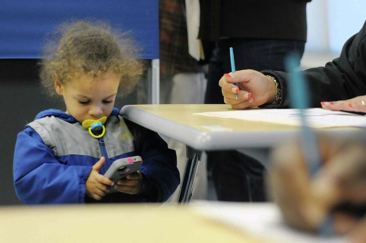 Joell-Damien Johnson, 2, plays a game on his mom's, Melissa Johnson, phone while she filled out her ballot at the polling station inside Green Tech High Charter School on Tuesday, Nov. 6, 2012 in Albany, NY. (Paul Buckowski / Times Union)